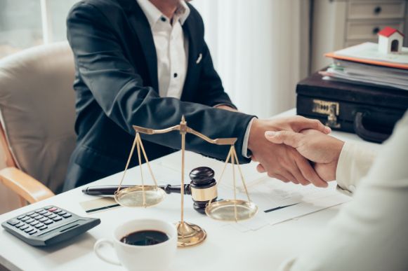 A Man in A Suit Is Shaking Hands with A Woman in Front of A Scale of Justice — Linda Emery & Associates In Tuggerah, NSW