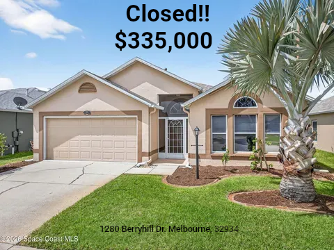 Suburban beige stucco house with two-car garage, front lawn, and palm tree in the yard
