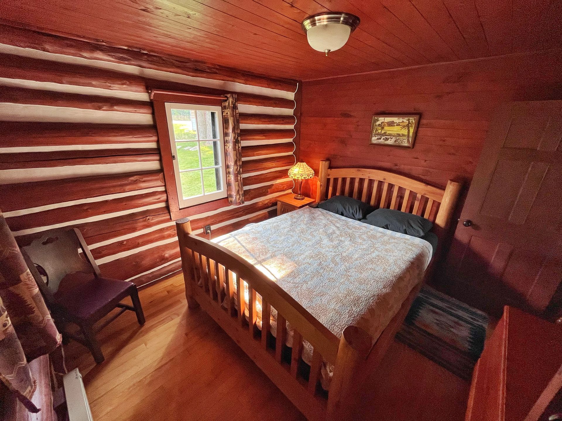 A bedroom in a log cabin with a bed and a chair.