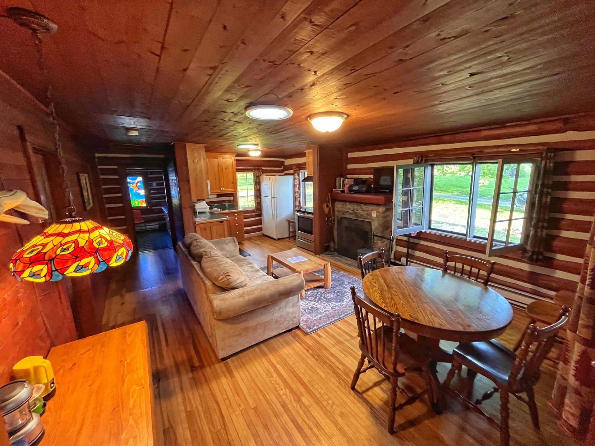 A living room in a log cabin with a couch , table and chairs.