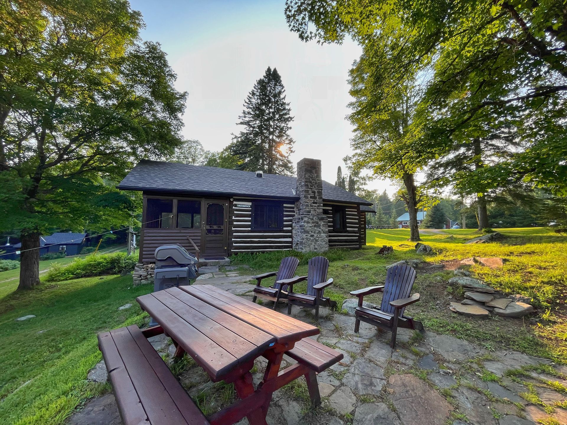 A log cabin with a picnic table and chairs in front of it