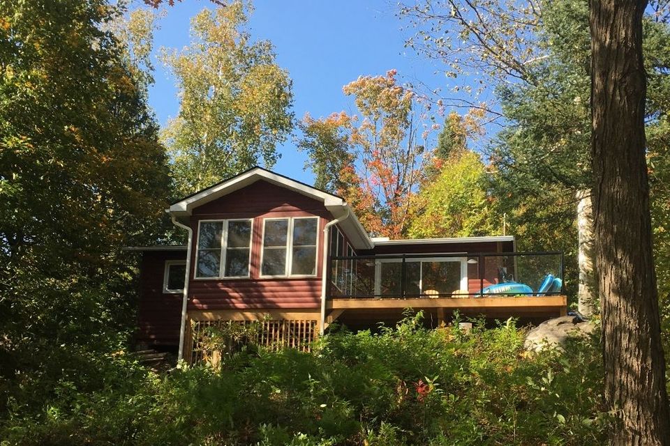 A white house with a red roof is surrounded by trees