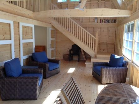 A room with chairs and a table with a staircase in the background