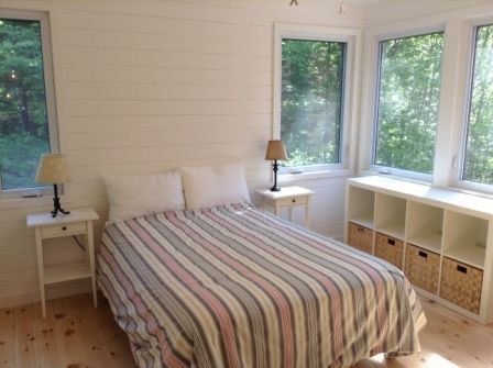A bedroom with a bed , two nightstands , and two windows.