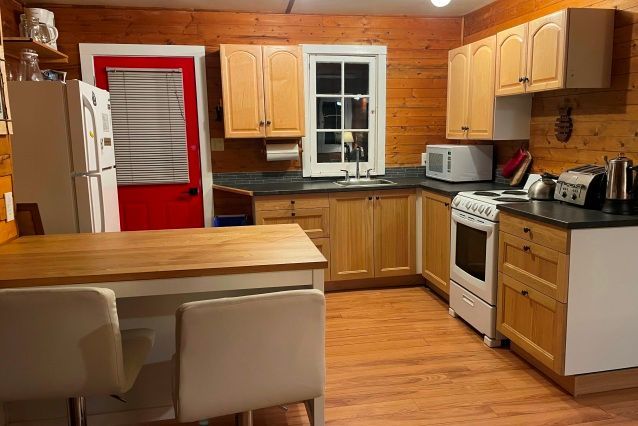 A kitchen with wooden cabinets and a red door.