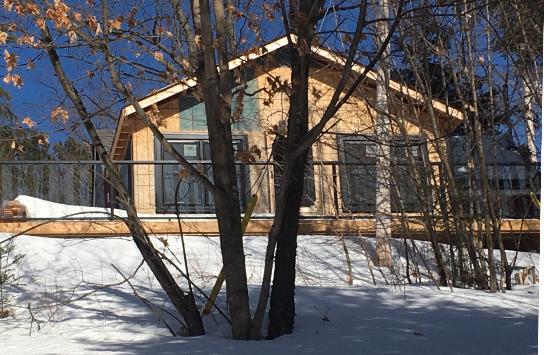 A small wooden house is surrounded by snow and trees.