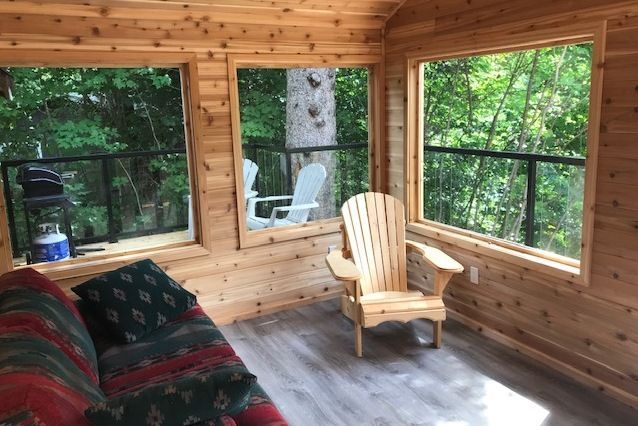 A living room with a couch , chair , and lots of windows.