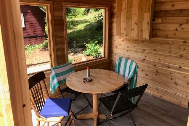 A wooden room with a table and chairs and a window.