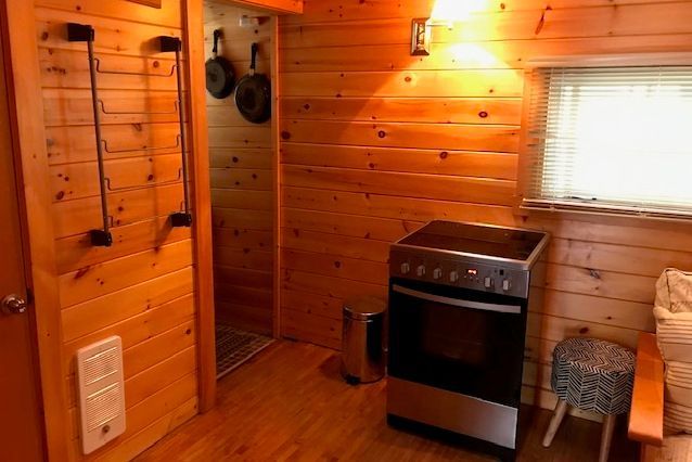 A kitchen in a log cabin with a stove and oven.