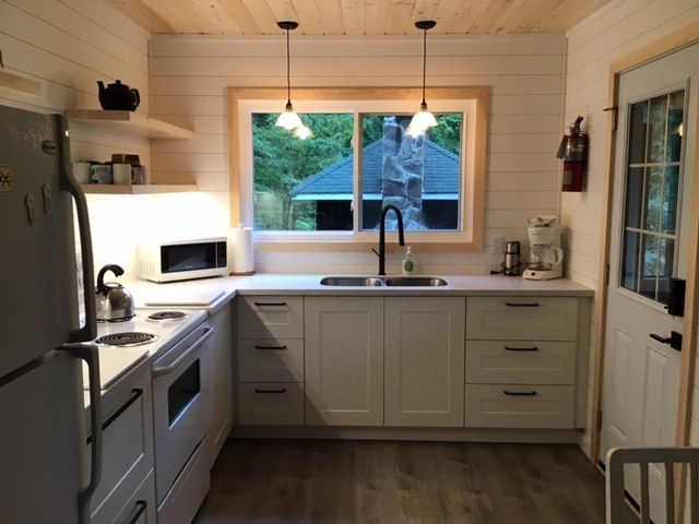 A kitchen with white cabinets a refrigerator and a window