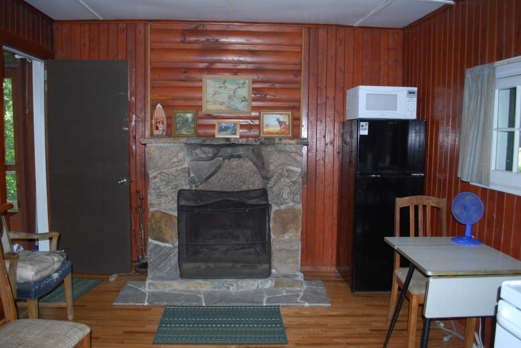 A living room with a fireplace and a black refrigerator