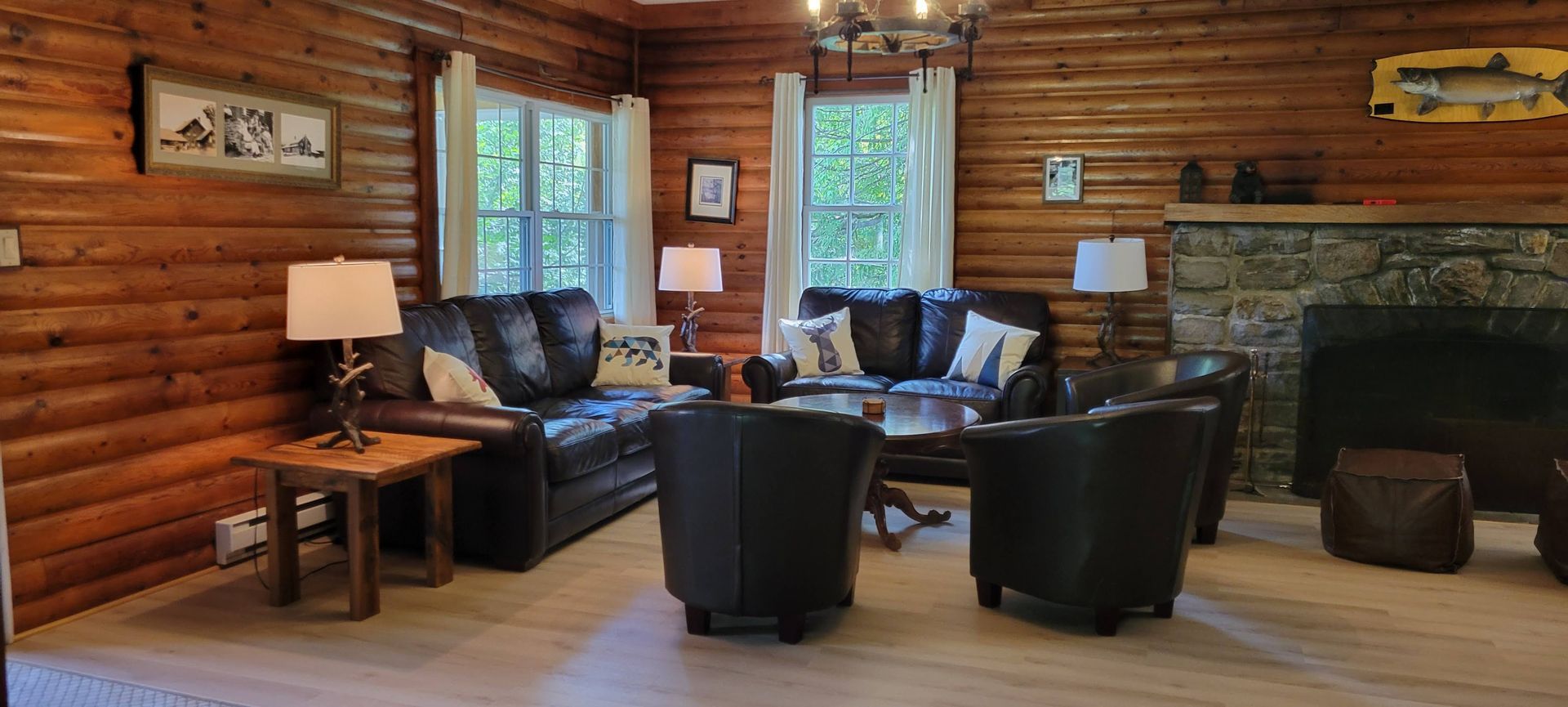 A living room in a log cabin with brown leather couches and chairs