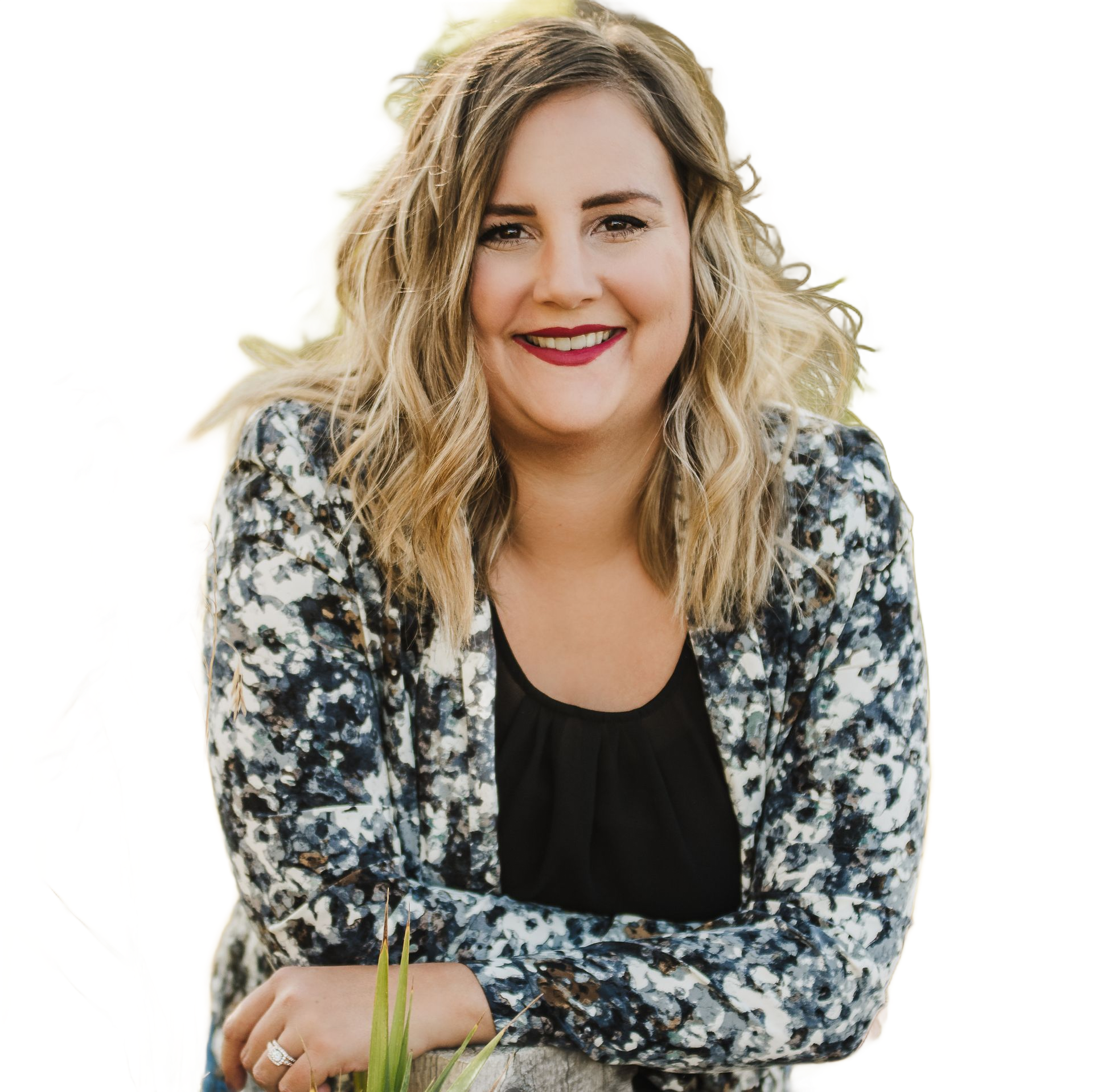 Smiling person with wavy blonde hair in a floral cardigan, seated against a white background