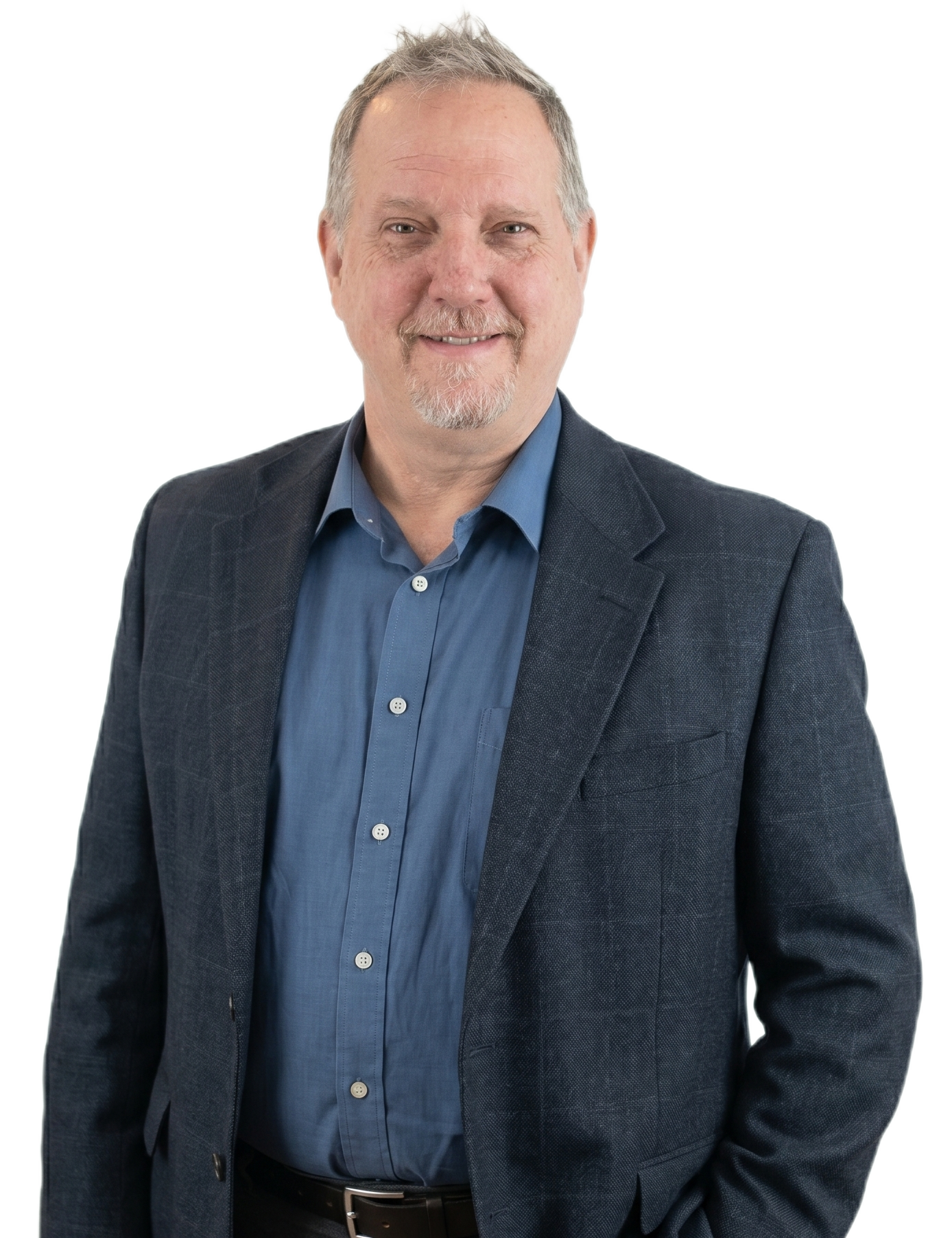 Smiling man in a blue shirt and dark blazer, standing against a white background.