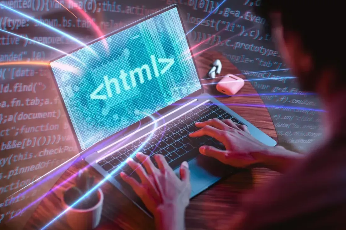 Hands typing on a laptop displaying HTML code, with neon code graphics around it.
