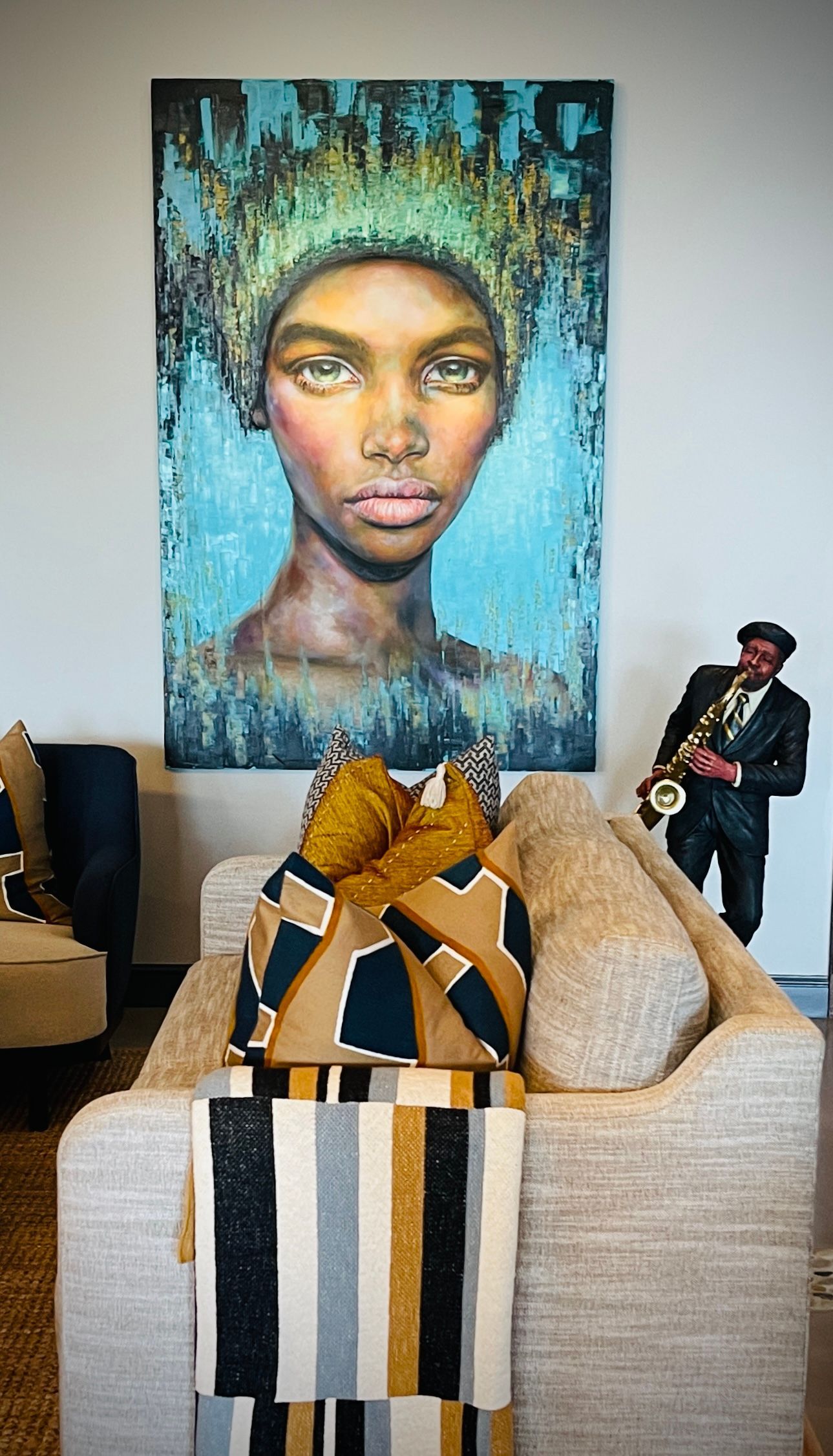 A living room with a couch and a painting of a woman on the wall.