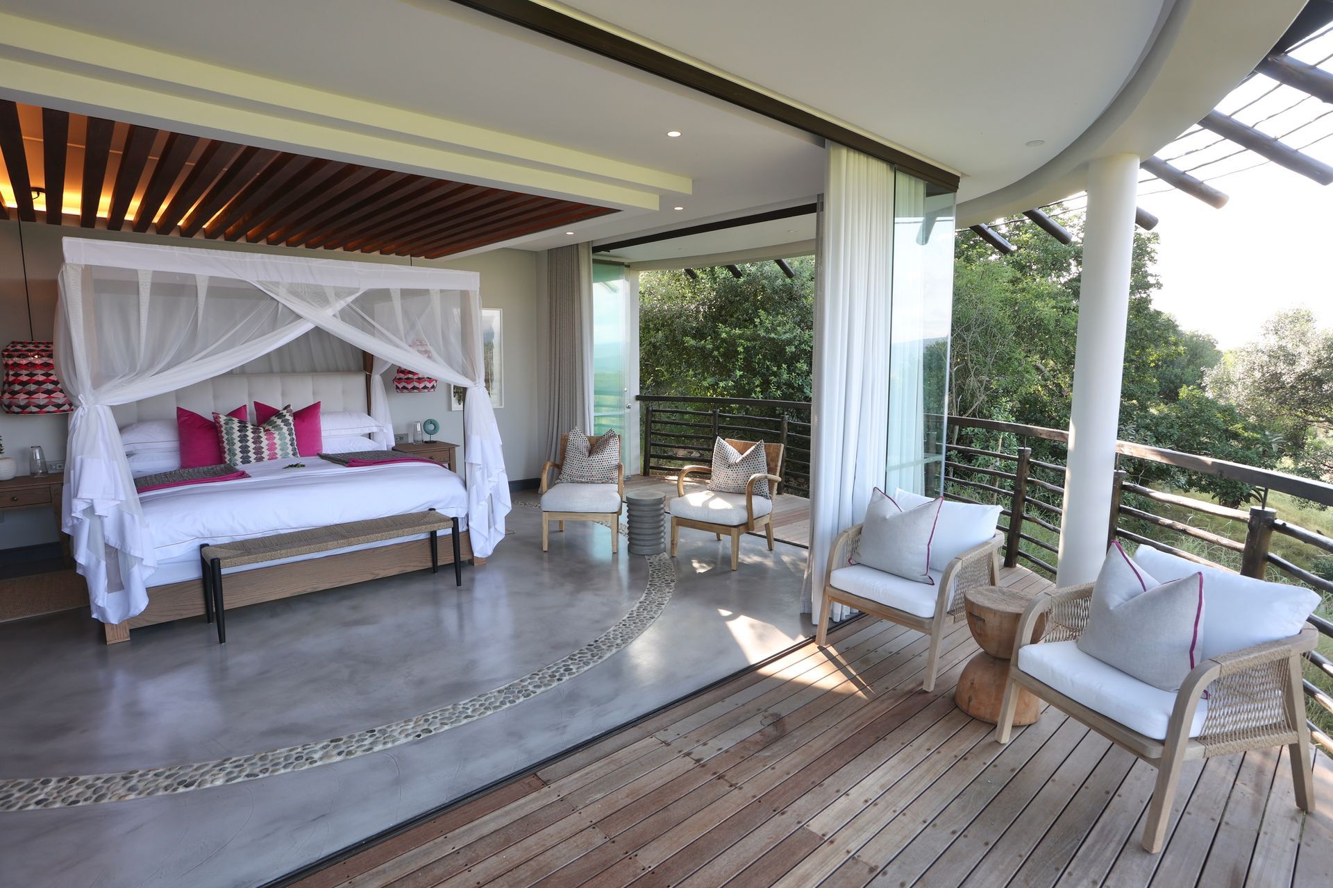 A bedroom with a canopy bed and chairs on a balcony.