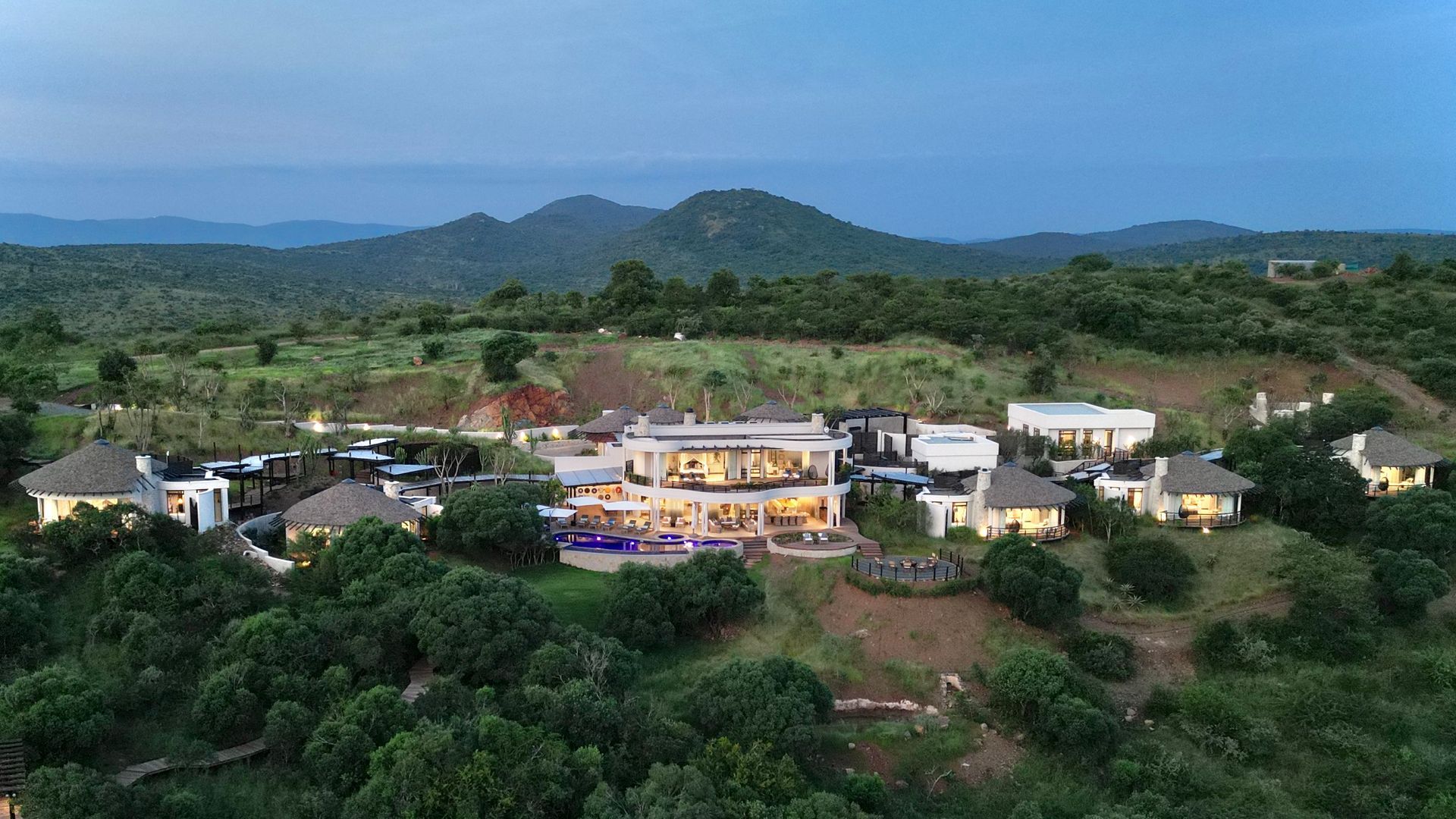 An aerial view of a large house on top of a hill surrounded by trees.