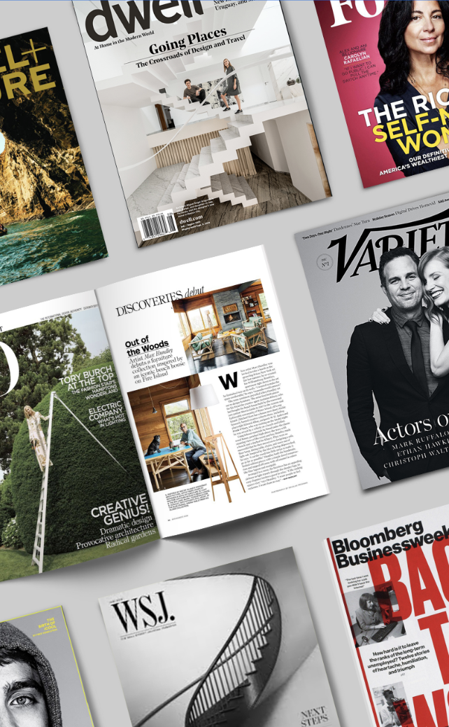 A variety of magazines are sitting on top of each other on a table.