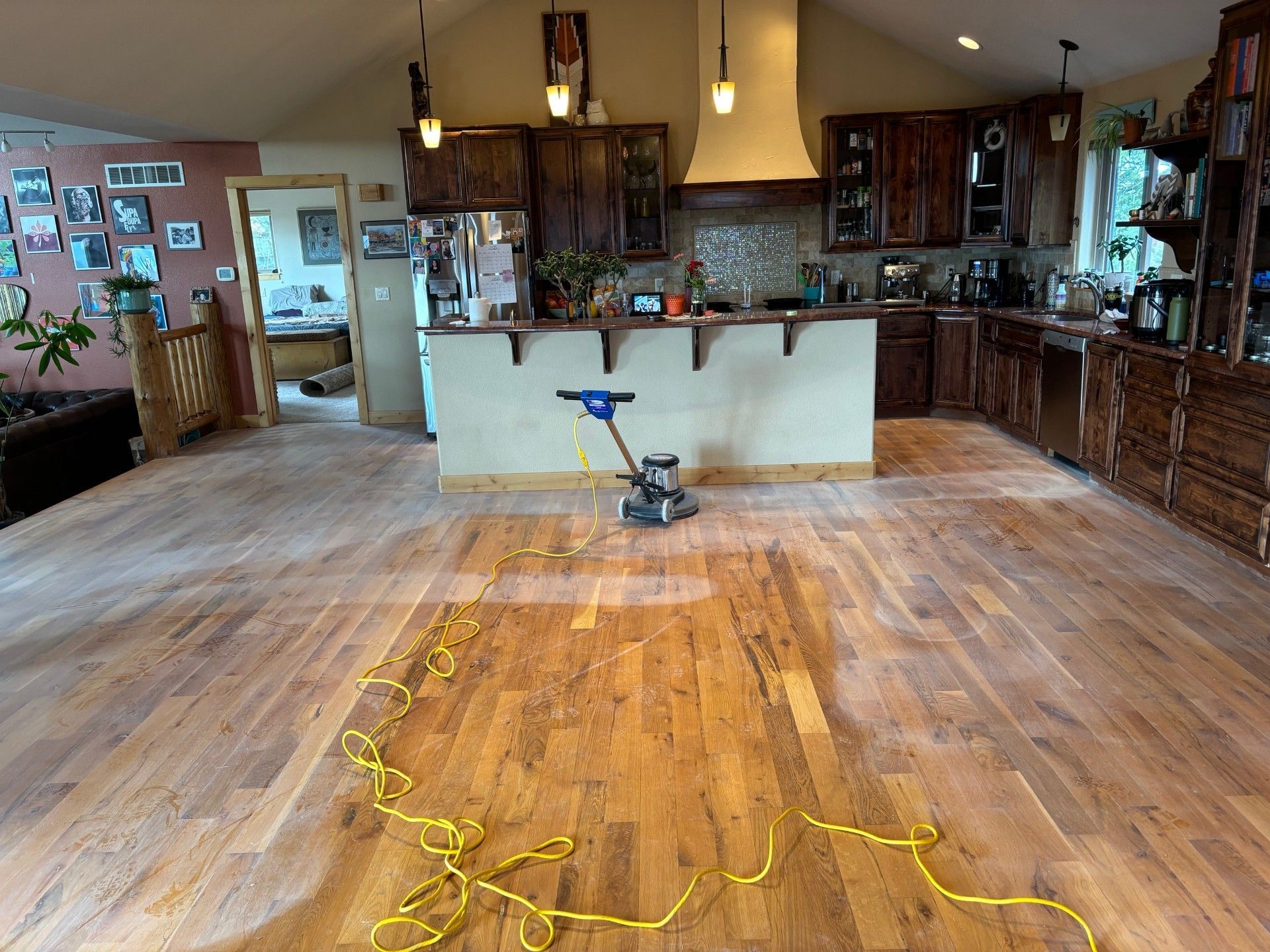 A kitchen with hardwood floors and a vacuum cleaner on the floor.