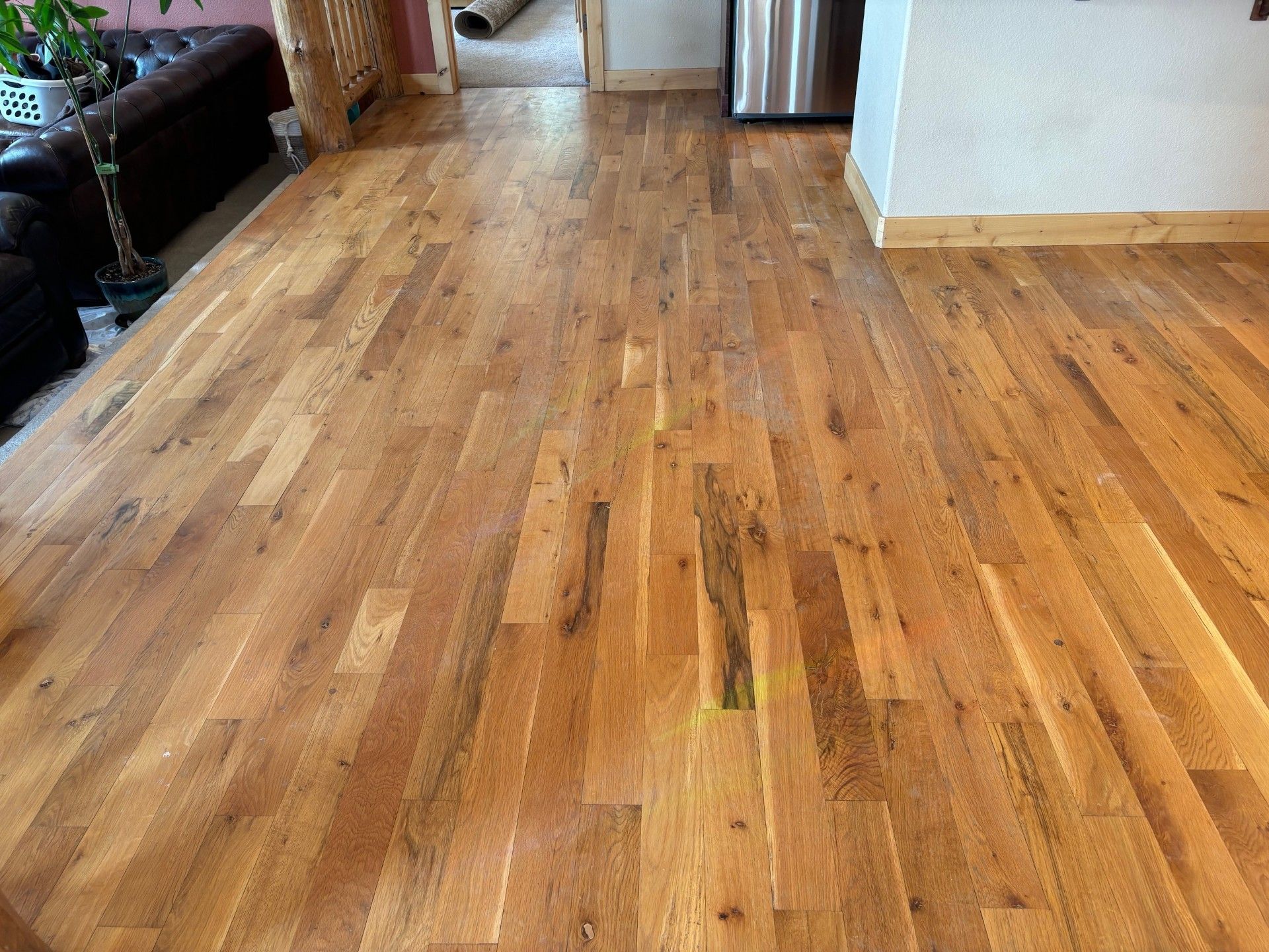 A living room with hardwood floors and a stainless steel refrigerator.