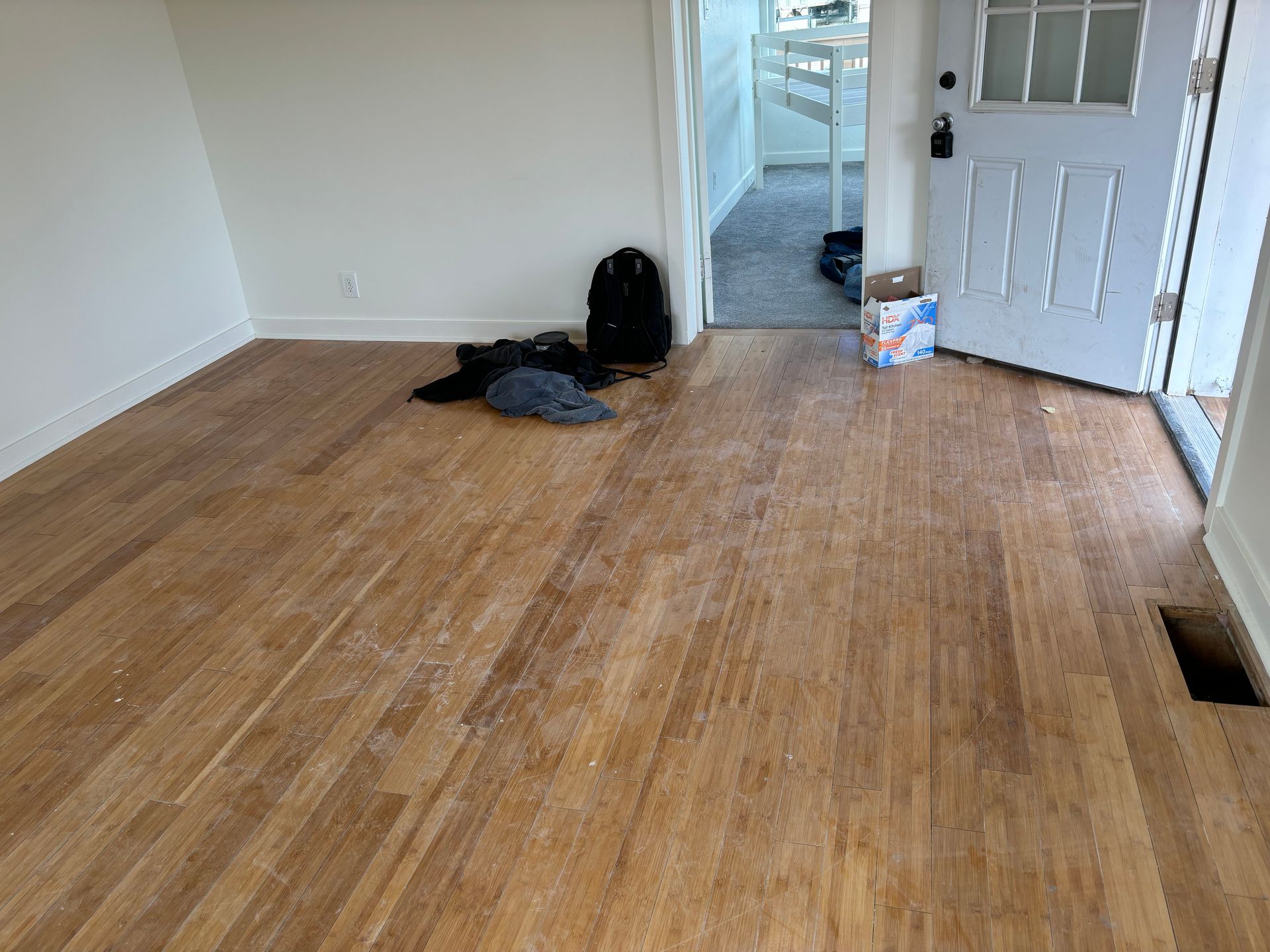An empty room with hardwood floors and a white door.