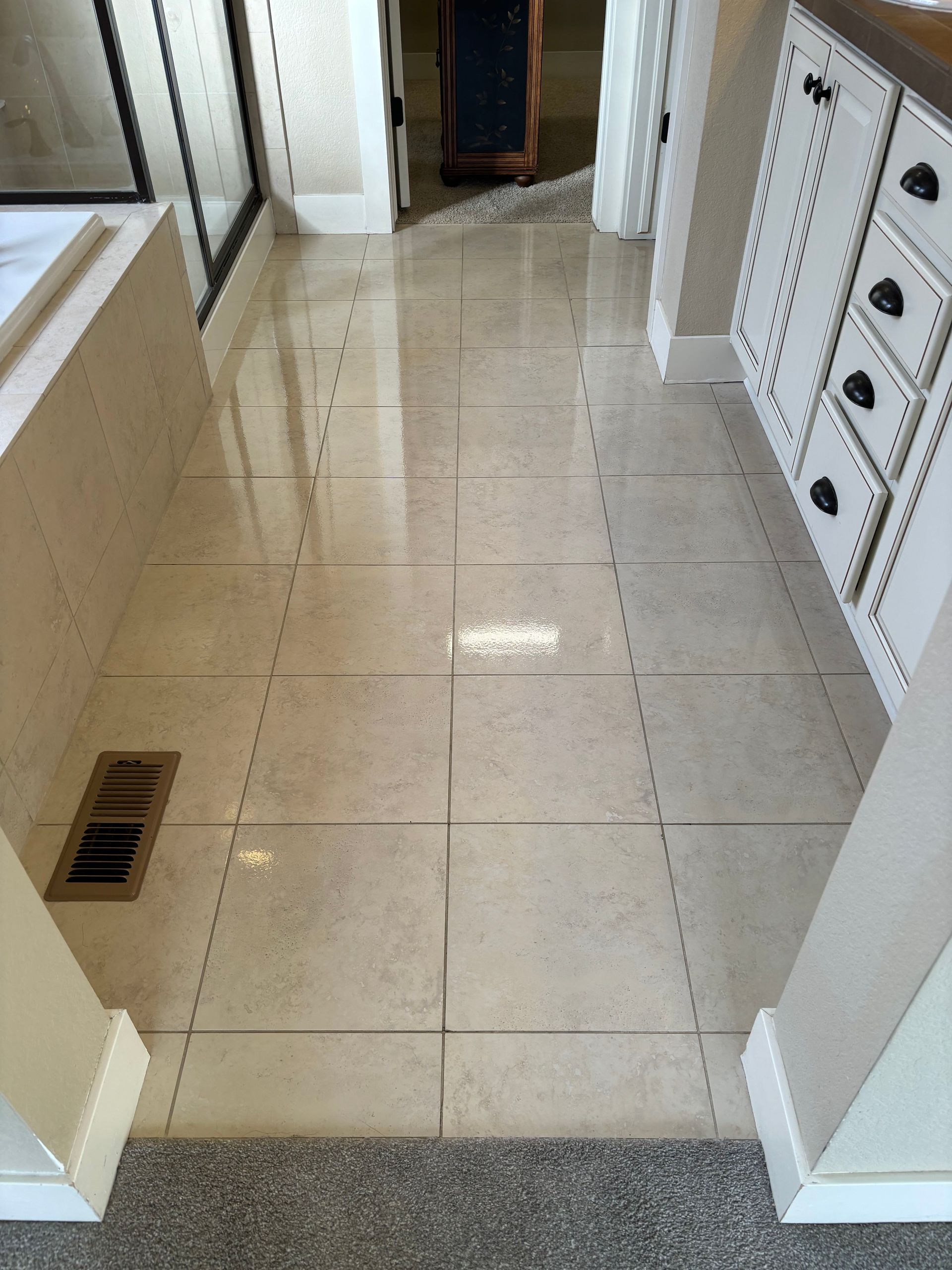 A bathroom with a tiled floor and white cabinets.