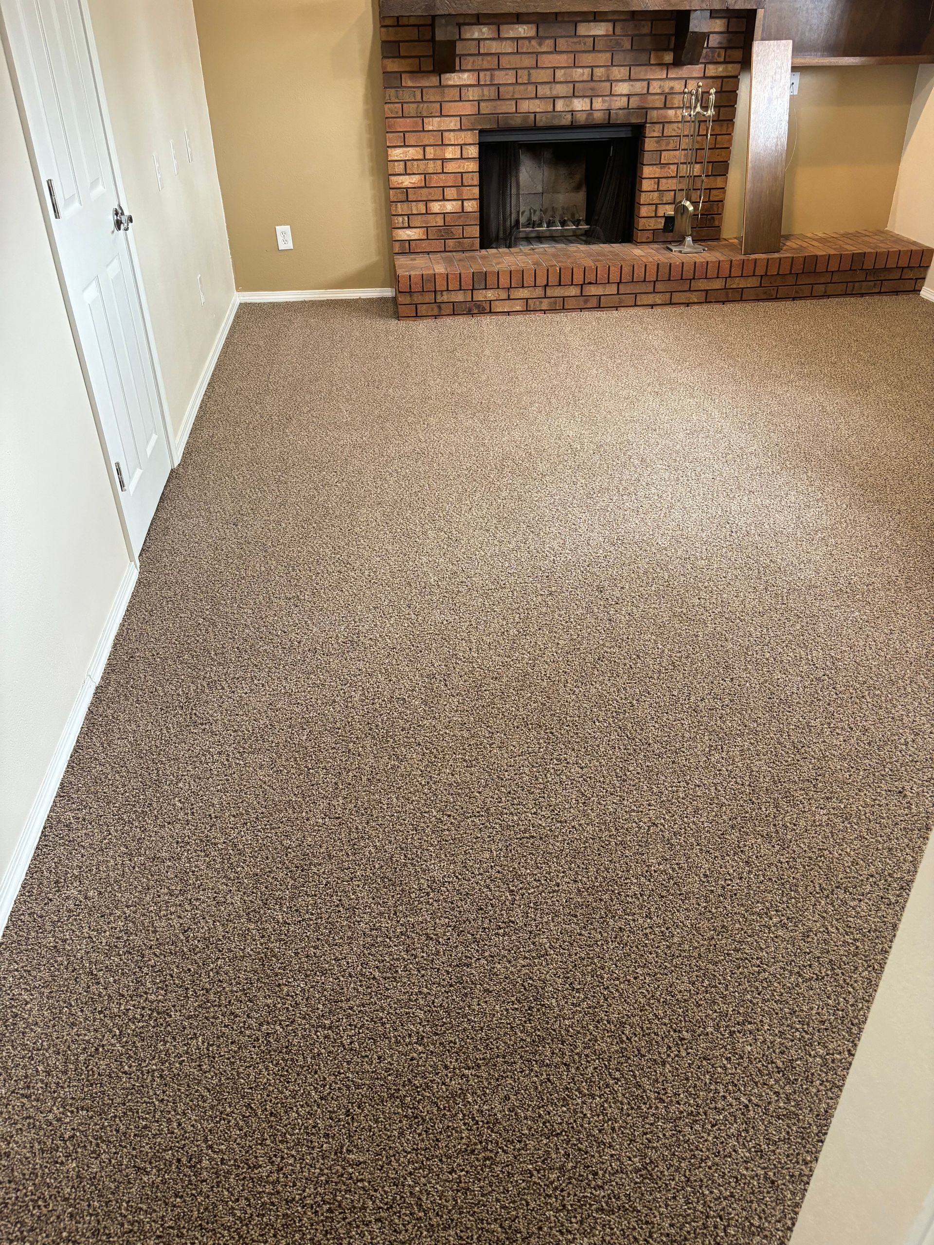 A living room with a fireplace and a carpeted floor.