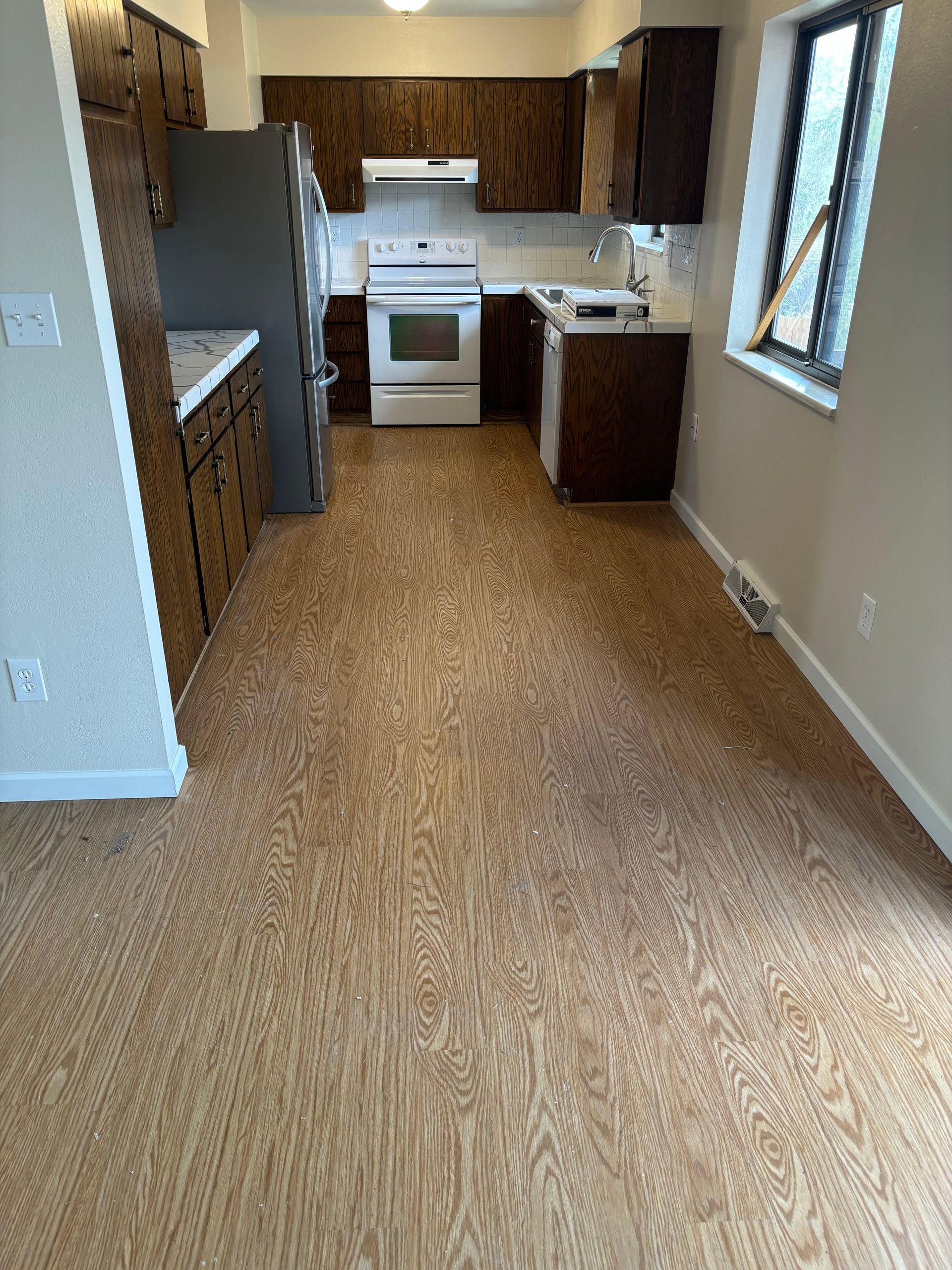 A kitchen with a cork floor and wooden cabinets.