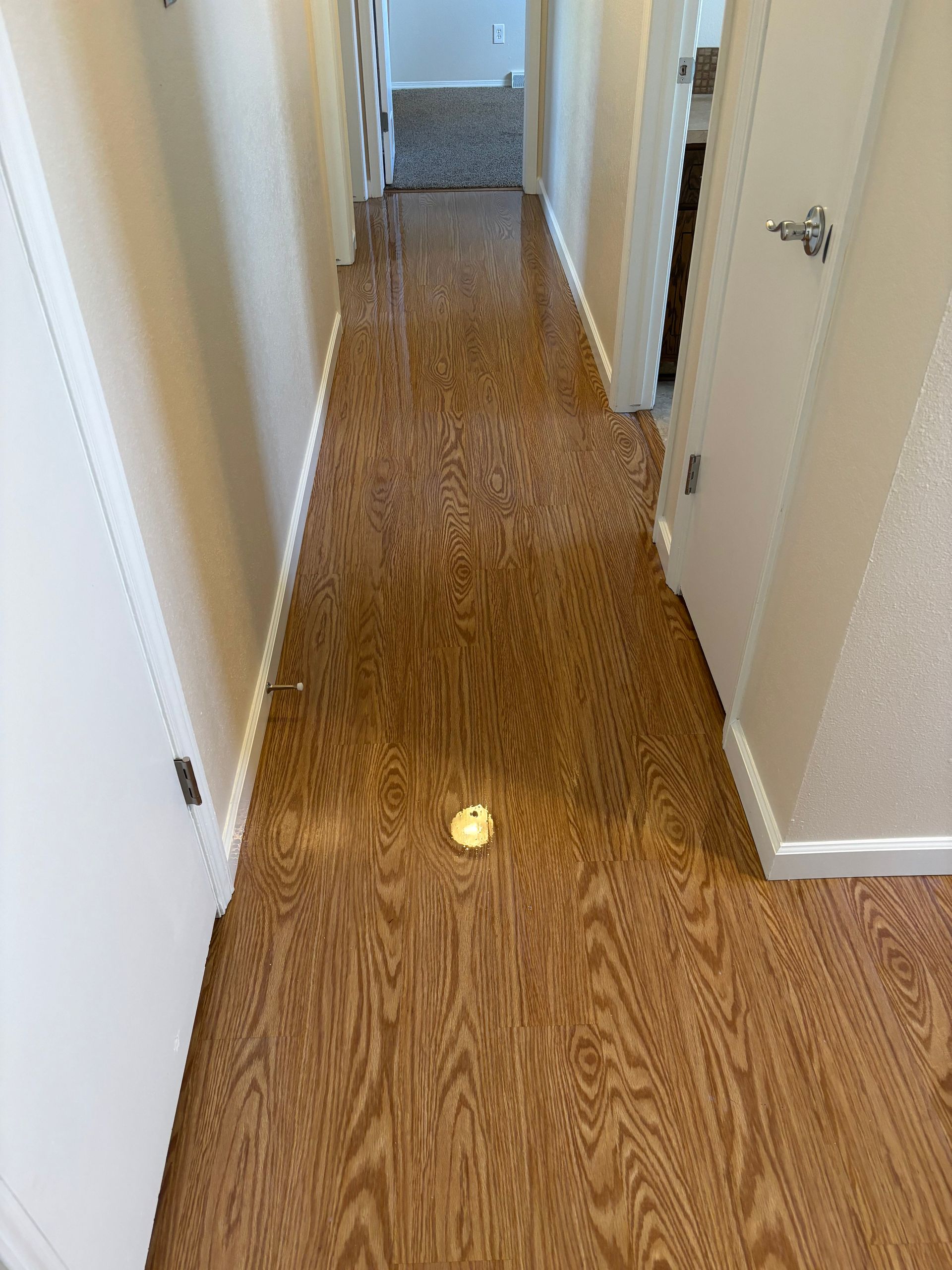 A long hallway with hardwood floors and white walls.