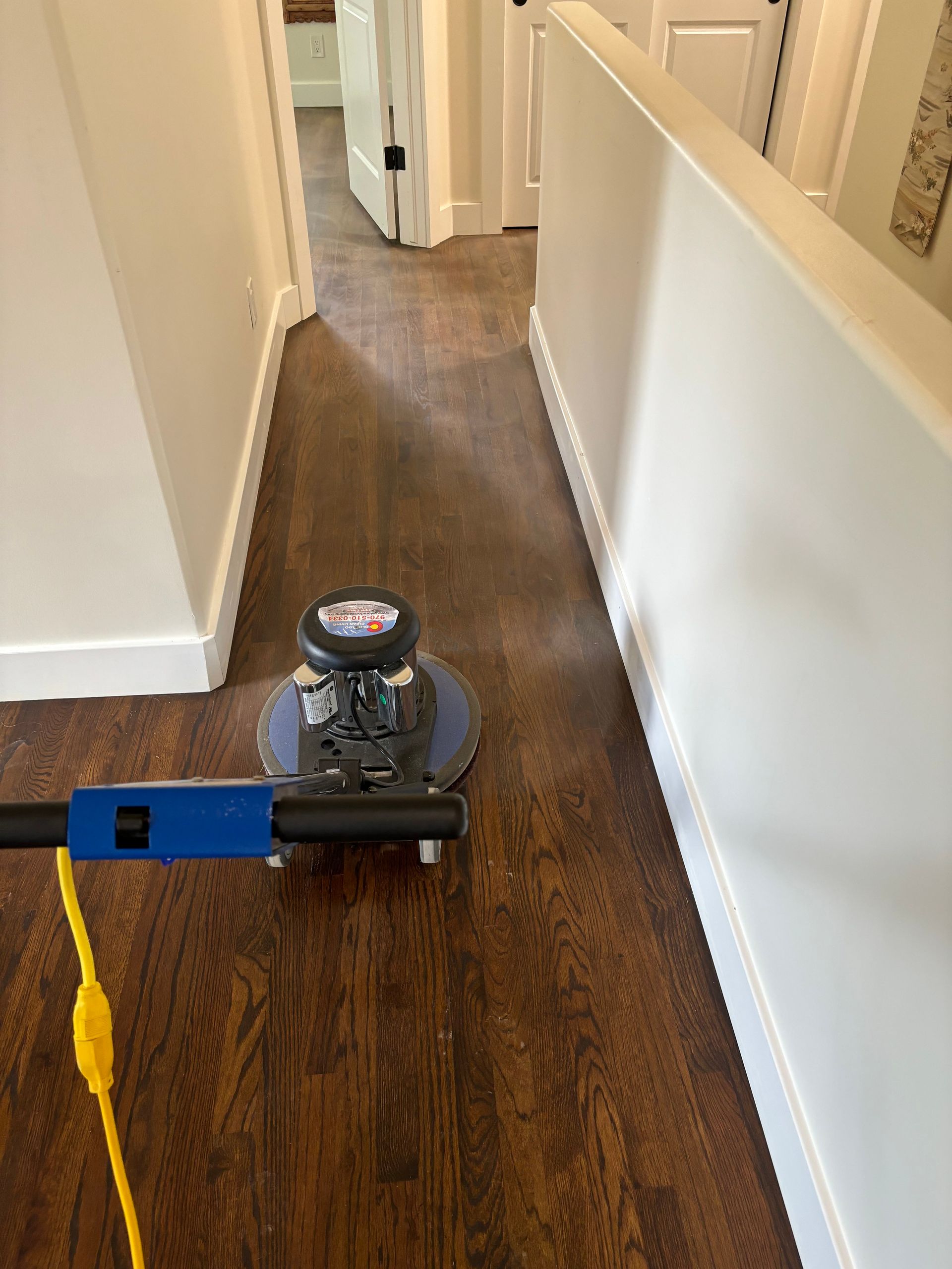 A machine is polishing a wooden floor in a hallway.