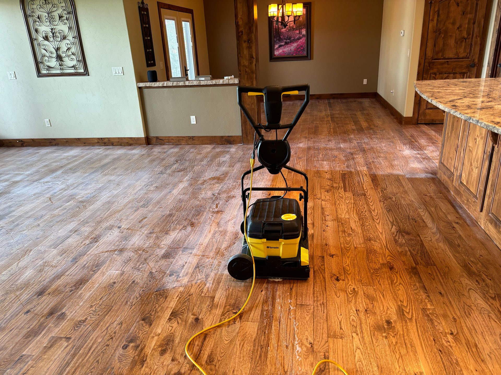 A yellow vacuum cleaner is sitting on a wooden floor in a living room.