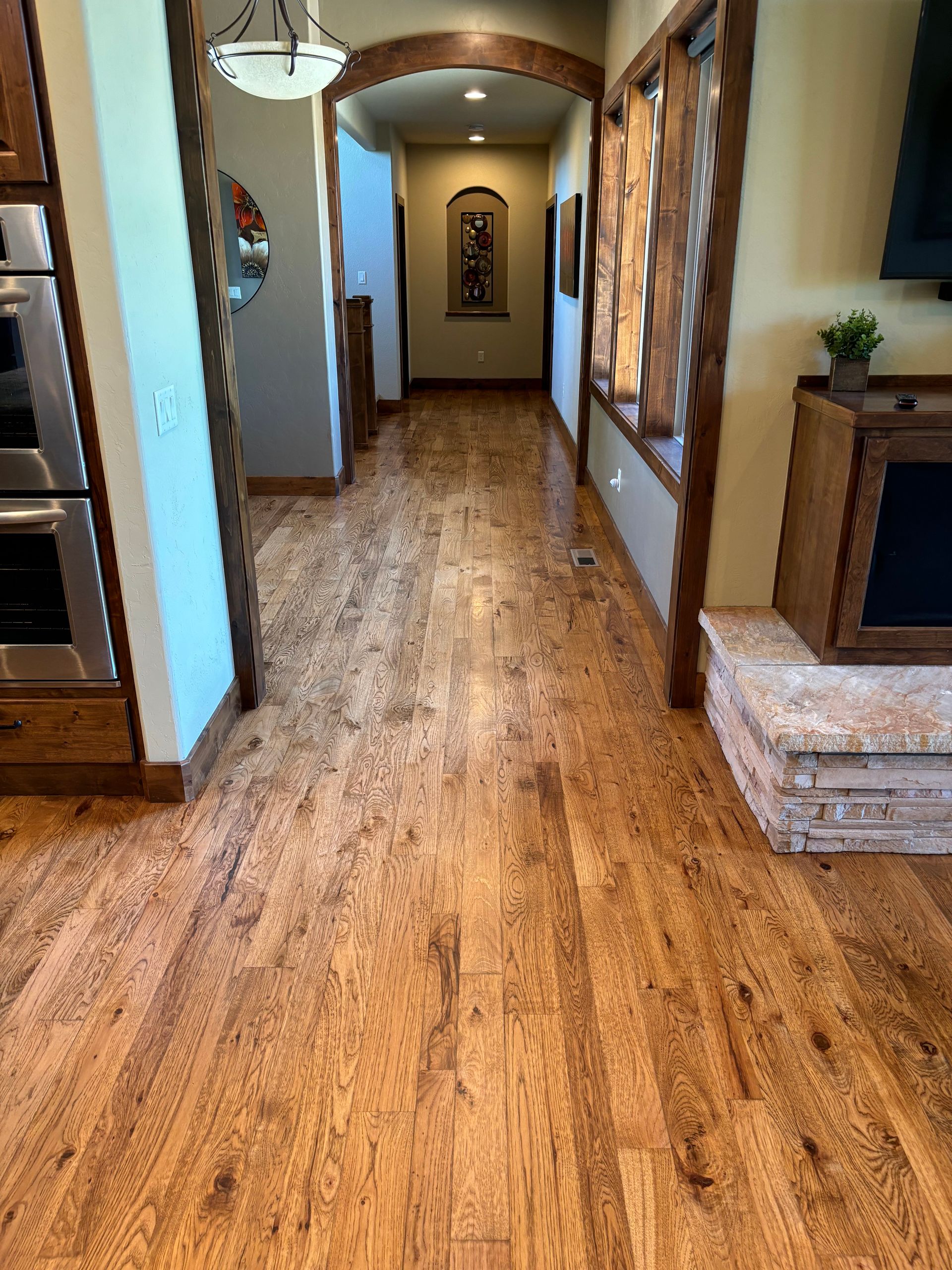 A hallway in a house with hardwood floors and a fireplace.