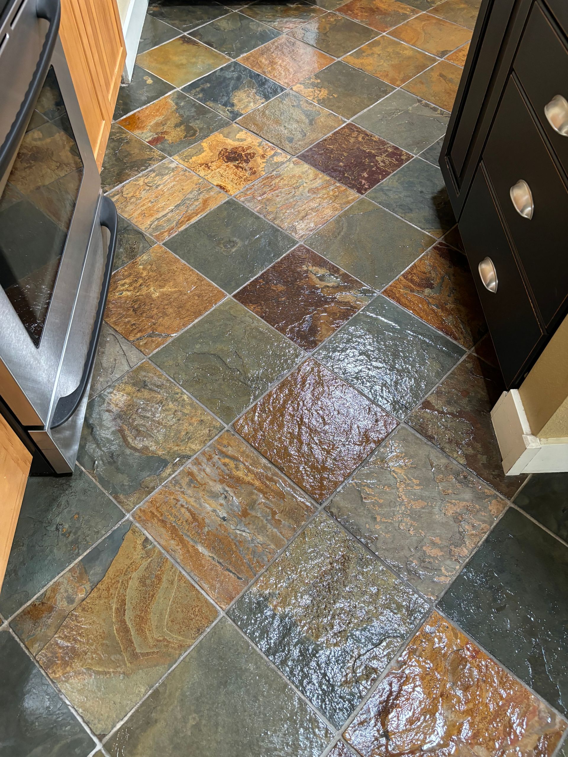 A kitchen floor with slate tiles and a stove.