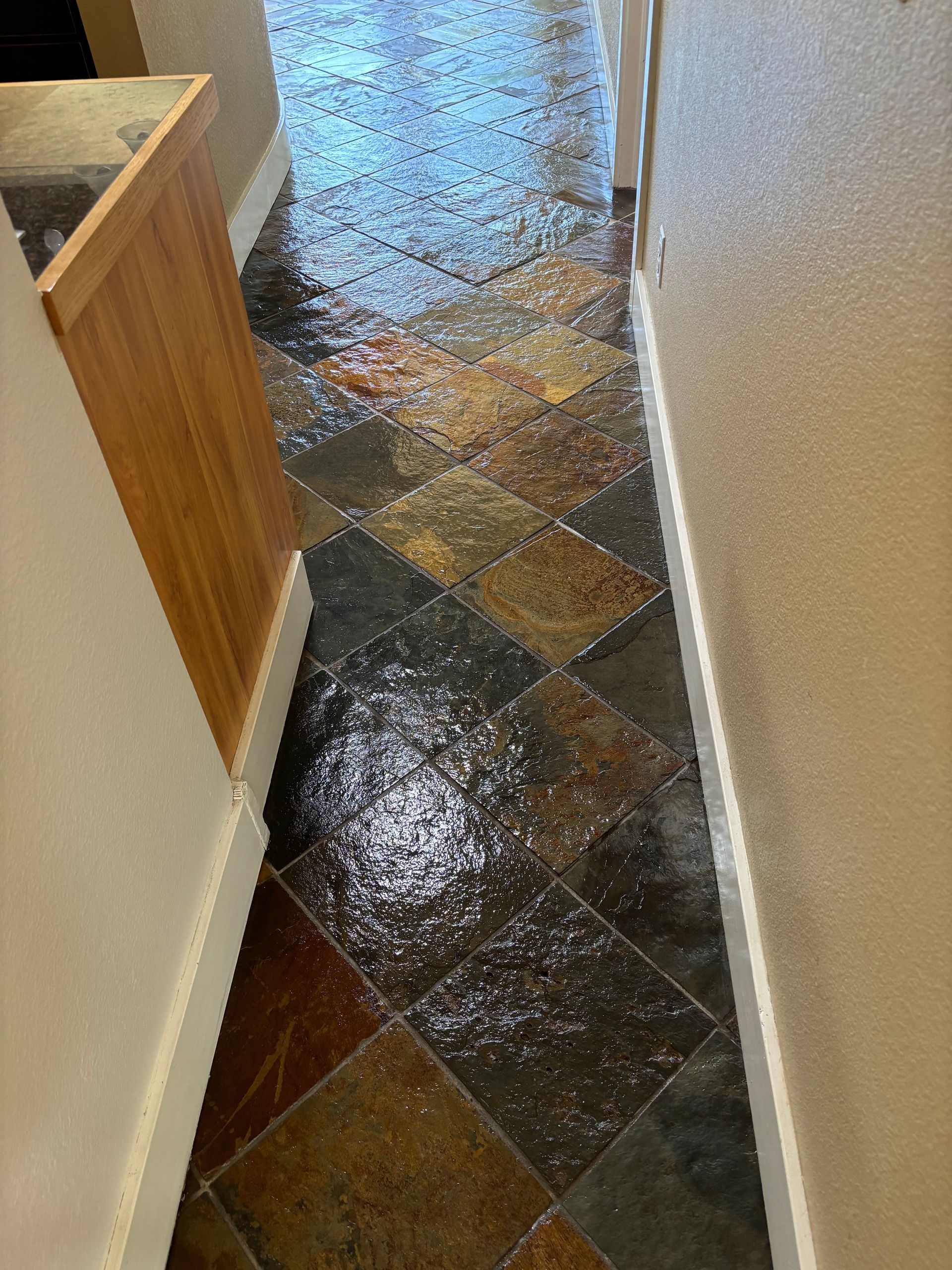 A hallway with a tiled floor and a wooden cabinet.