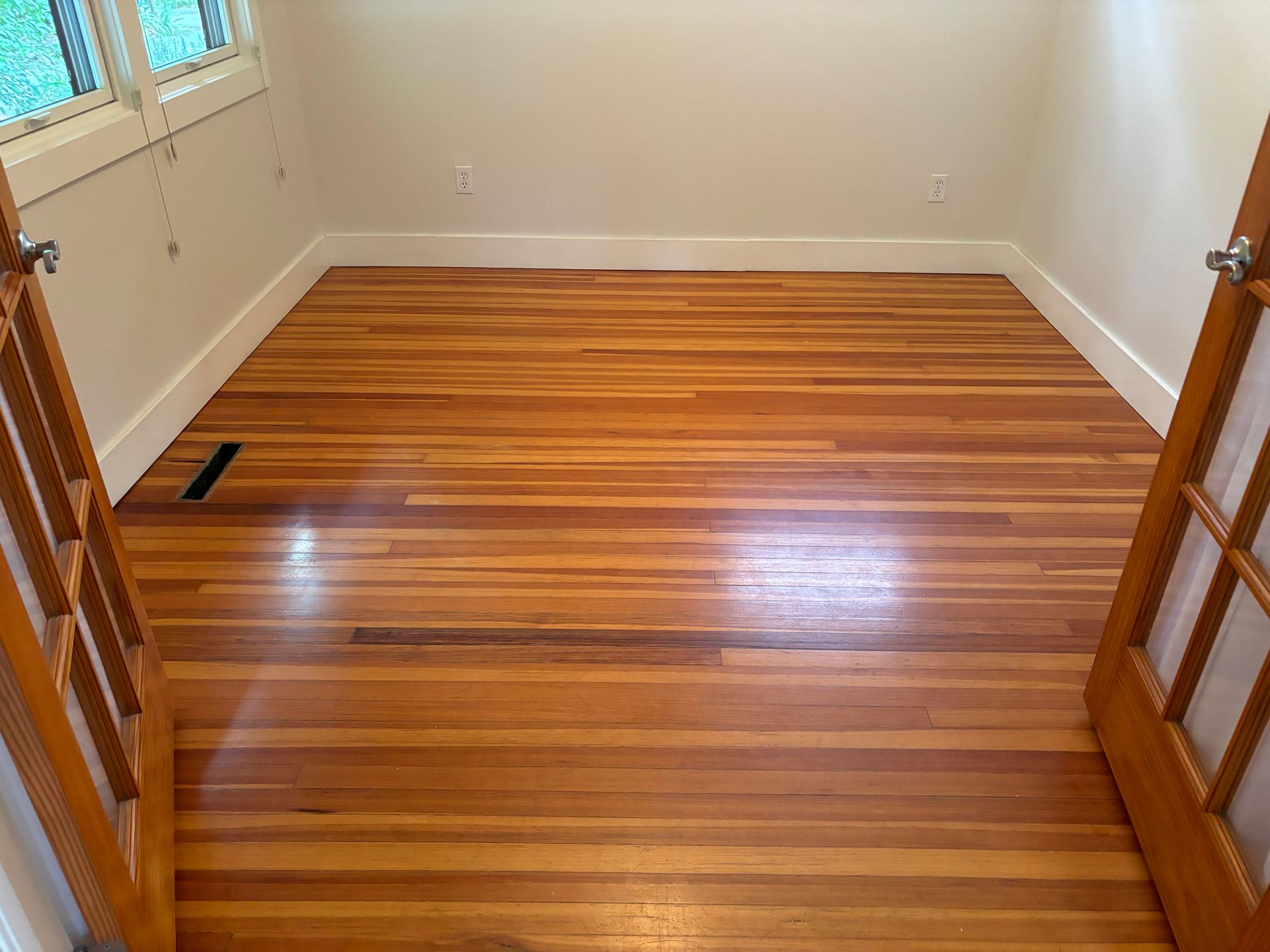 A room with a wooden floor and french doors.