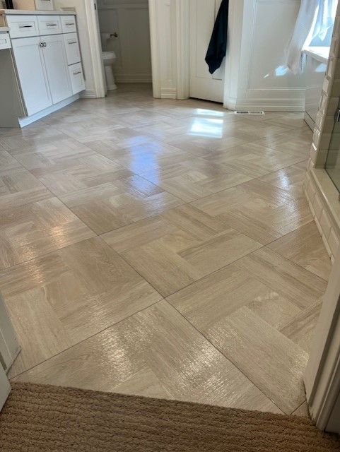 A bathroom with a herringbone tile floor and white cabinets.