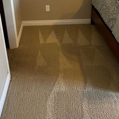 A bedroom with a bed and a carpeted floor.