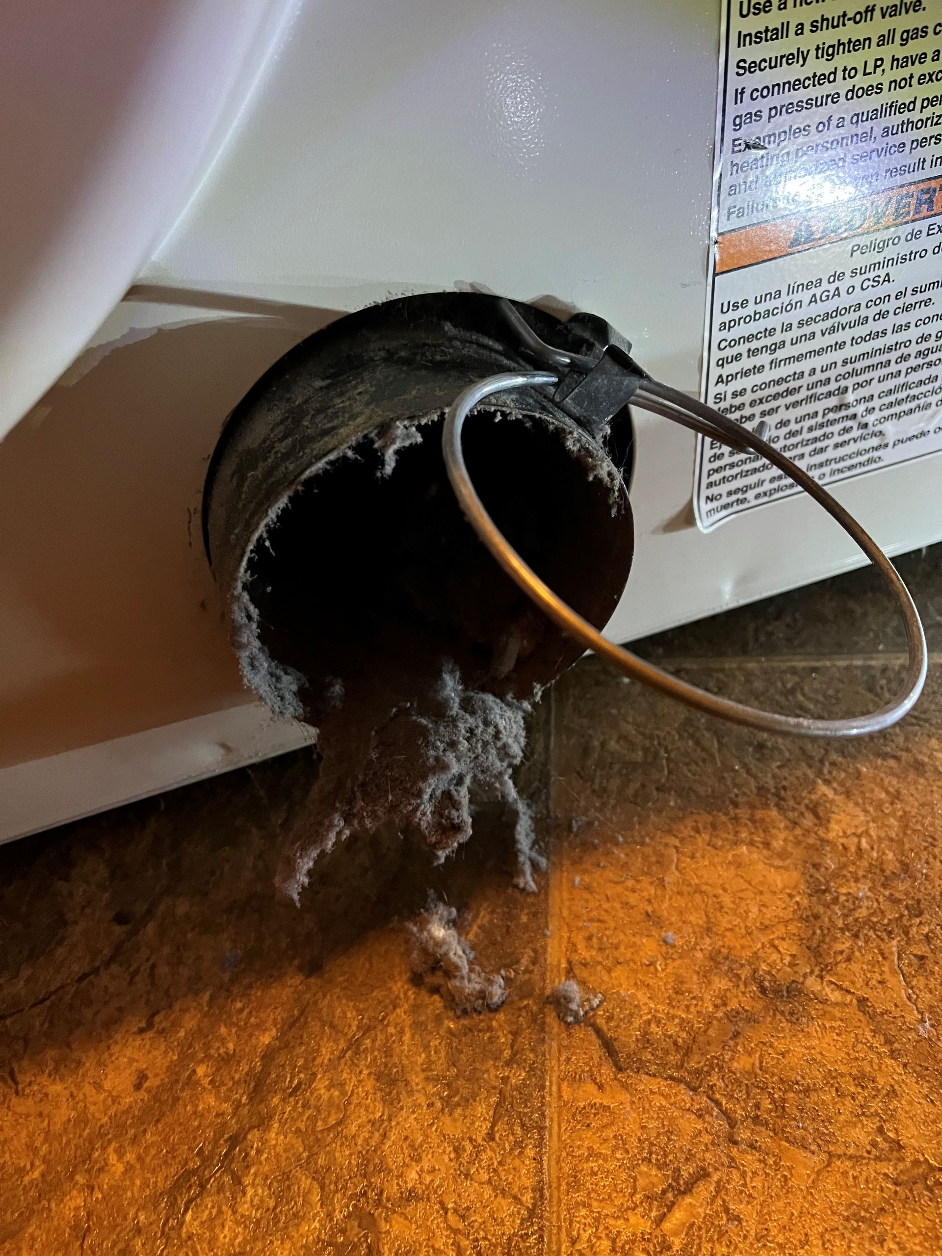A dirty pipe is coming out of a dryer.