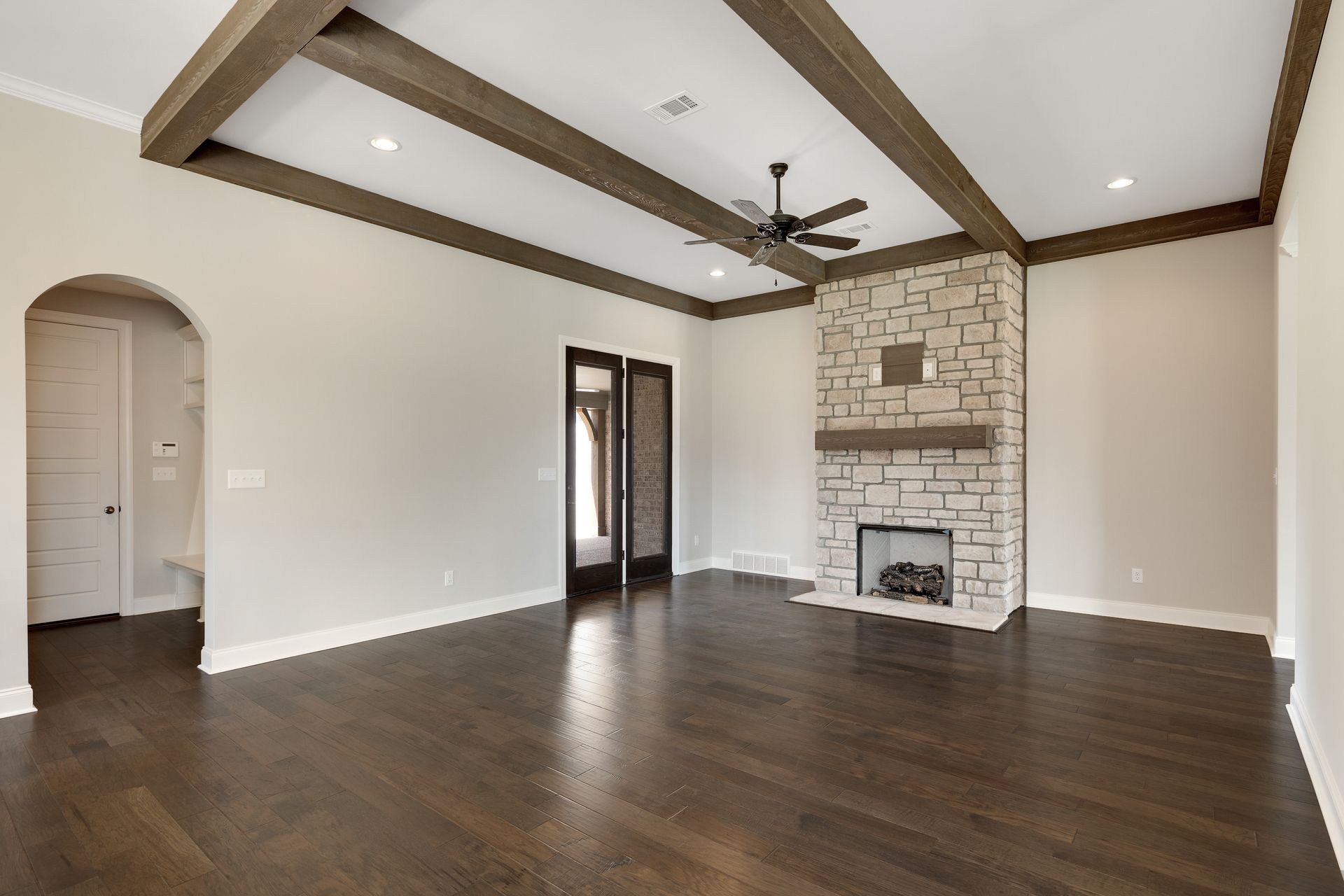 An empty living room with a fireplace and ceiling fan.