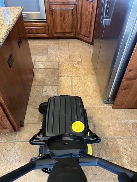 A black scooter is sitting on a tiled floor in a kitchen.