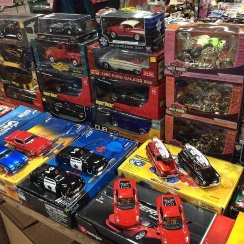 Display of assorted die-cast toy cars in colorful boxes and cases at a shop stall