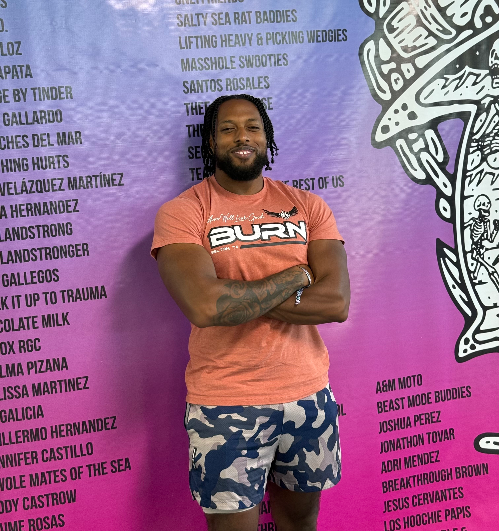 Woman in pink Nike shirt and black shorts stands in a locker room with team gear.