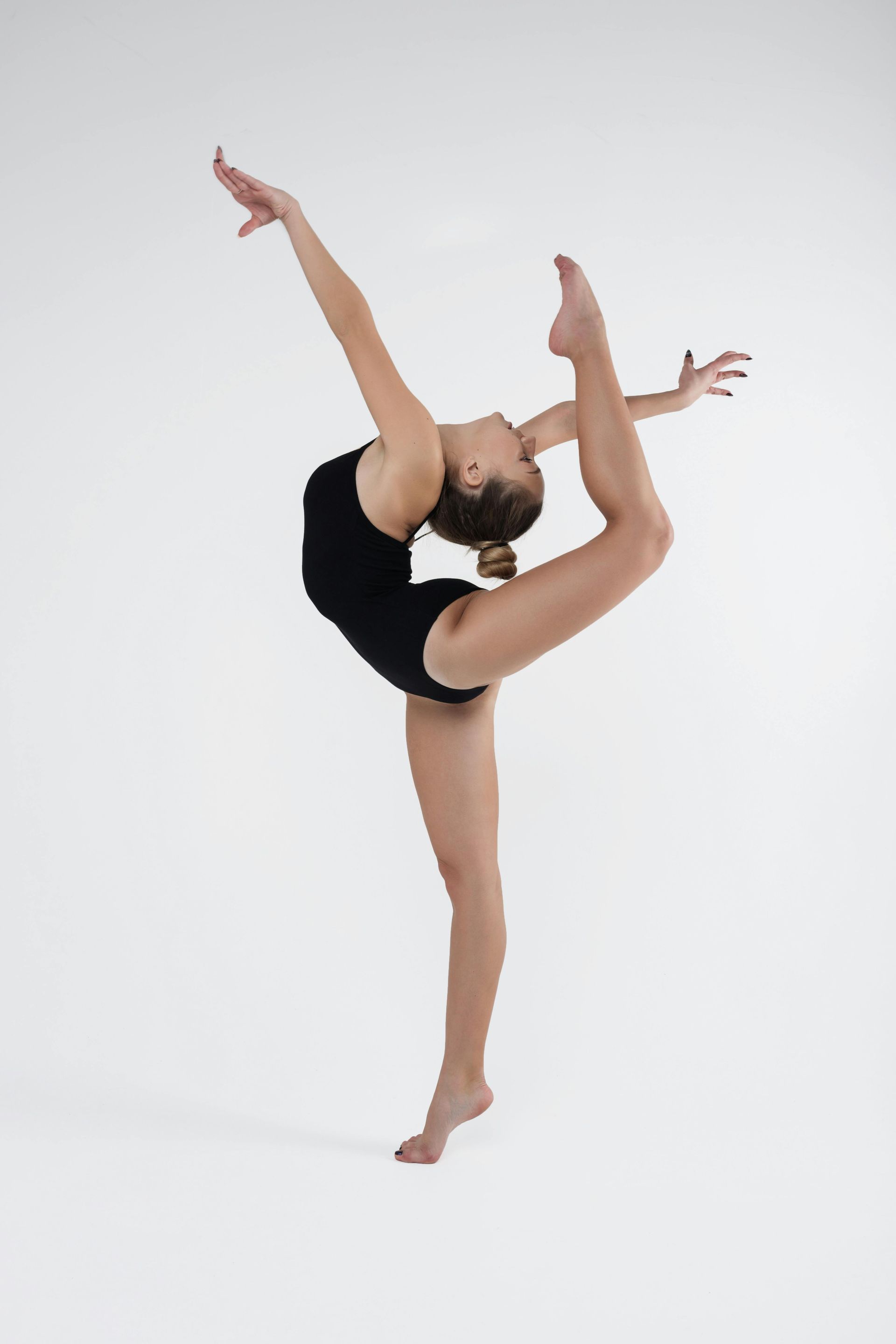 A dancer in a black leotard performs a balance pose with one leg arched overhead.