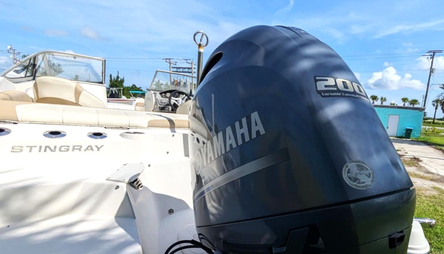 Blue Yamaha outboard motor on a white Stingray boat at a sunny marina with blue sky.
