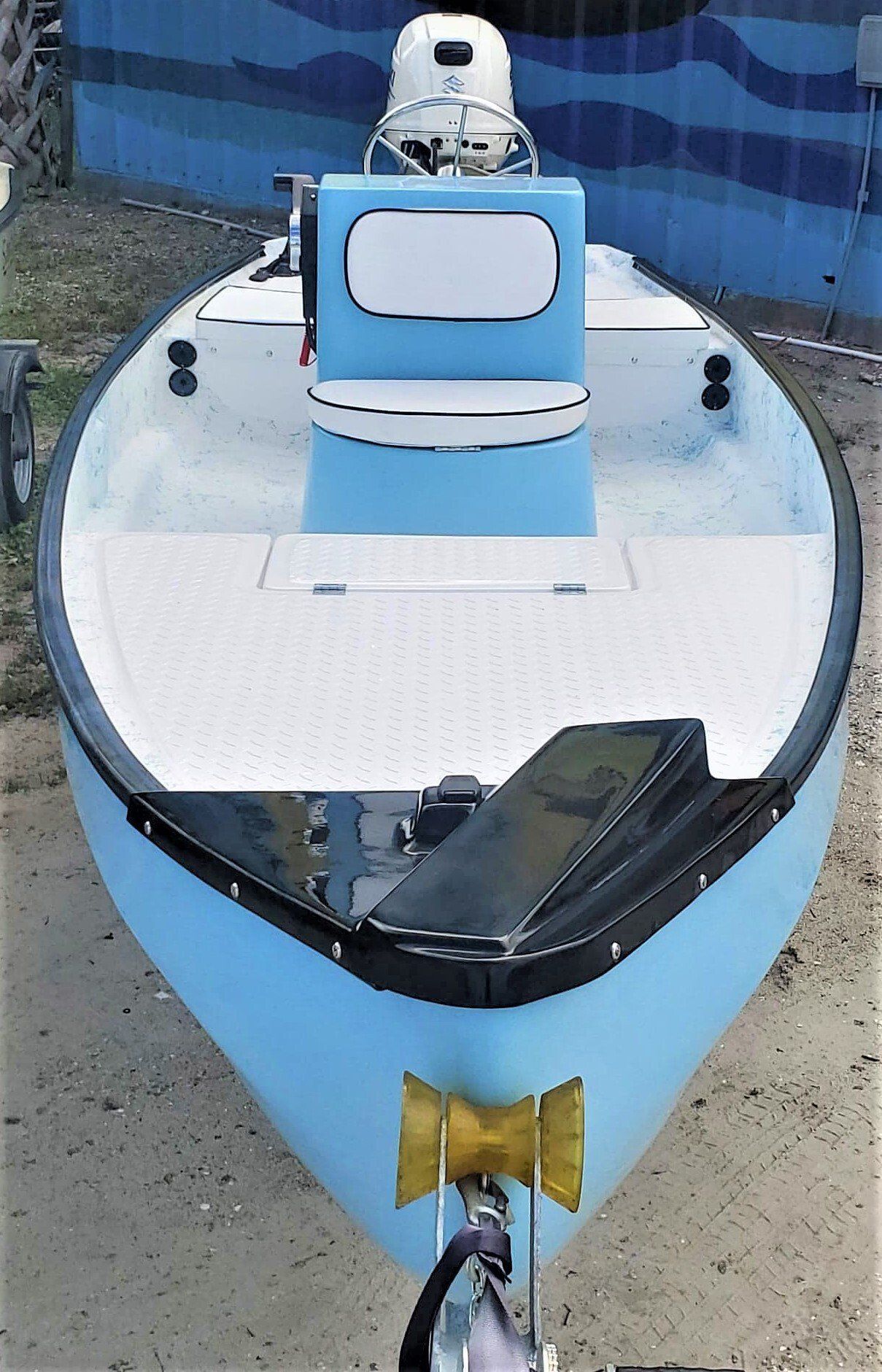 A light blue boat on a trailer, viewed from the front, featuring a white center console and interior deck.