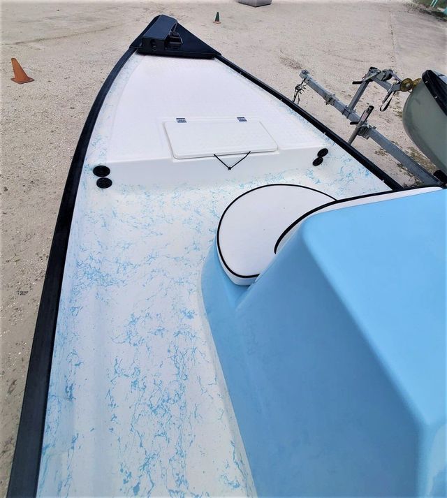 High-angle view of the interior of a light blue skiff boat featuring a white deck with blue splatter-pattern non-skid.