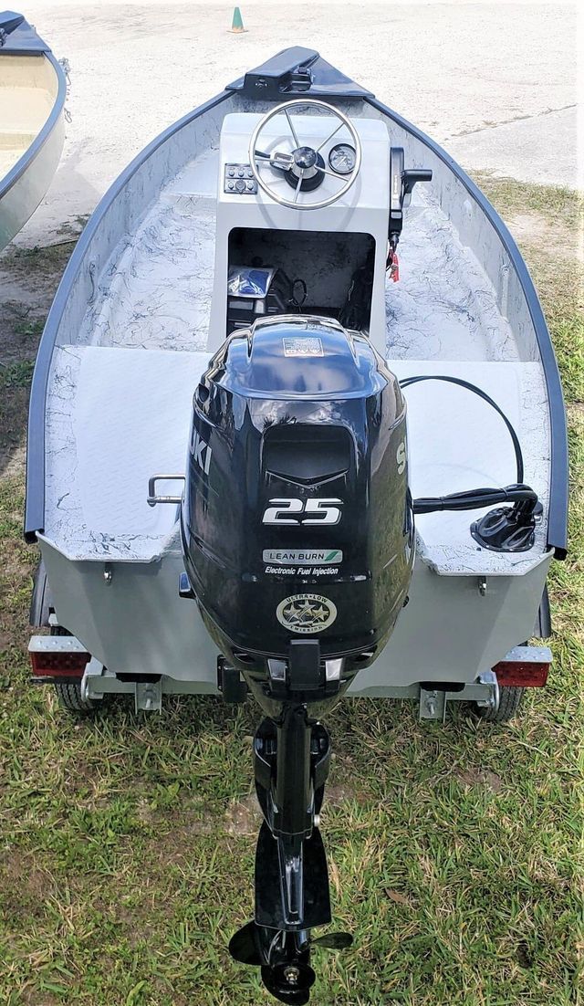 A silver motorboat on a trailer with a black Suzuki 25-horsepower outboard motor attached, viewed from the rear.