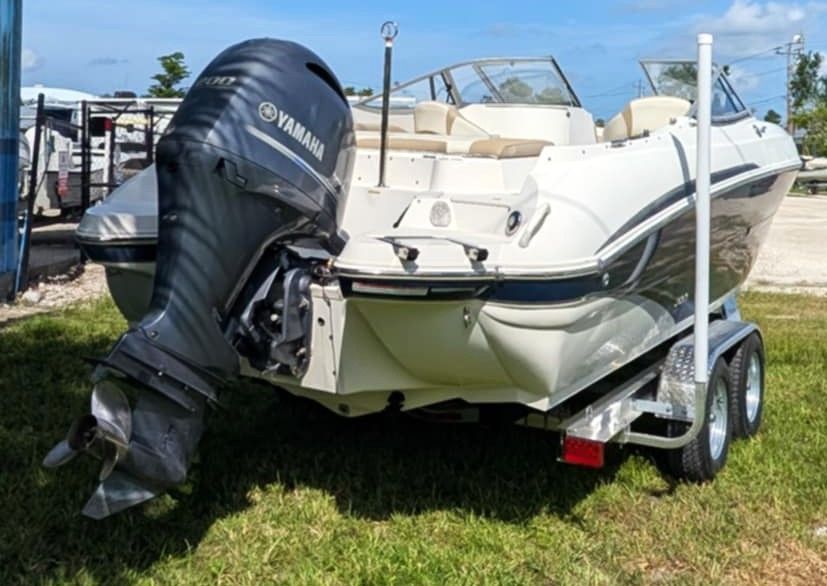 White boat on trailer with black Yamaha outboard motor parked on grass