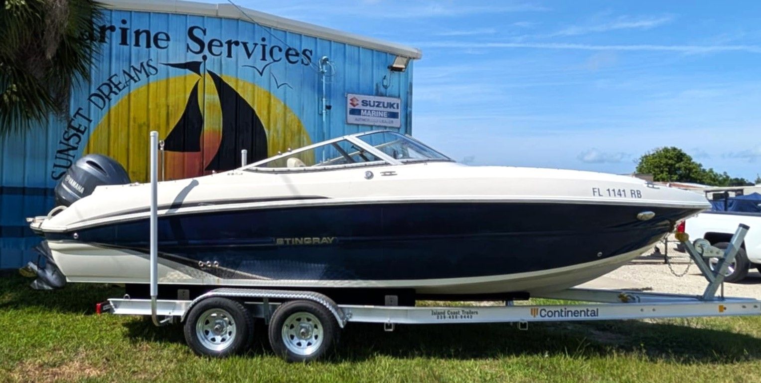 White and navy speedboat on a trailer outside a marine services building under a blue sky